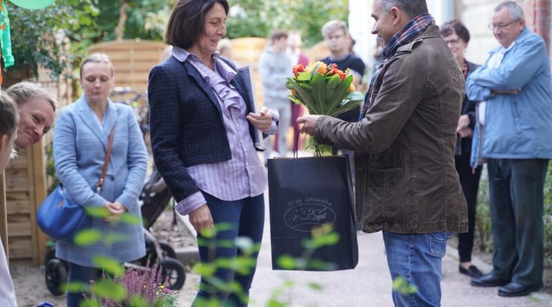 mężczyzna wręcza kobiecie kwiaty oraz torbę z upominkami