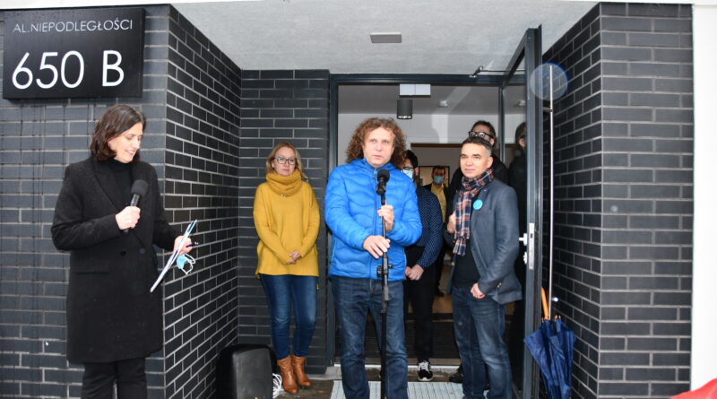 grupa osób stoi przed wejściem do mieszkania