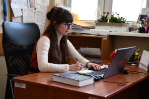 kobieta siedzi przy biurku przed laptopem