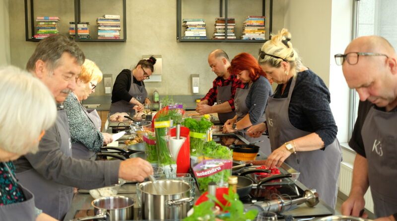 grupa osób w kuchni przygotowuje potrawy