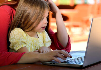 kobieta z dzieckiem siedzi przed laptopem