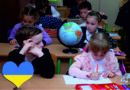 dzieci siedzą w ławkach szkolnych