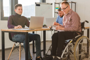 grupa mężczyzn pracujących razem w biurze z osobą na wózku inwalidzkim