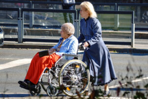kobieta pcha wózek inwalidzki ze starszą kobietą