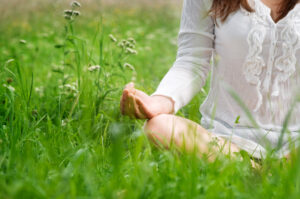 kobieta siedzi na trawie i medytuje
