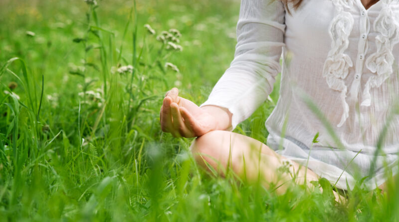 kobieta siedzi na trawie i medytuje