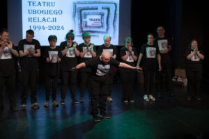 grupa osób stoi na scenie teatralnej