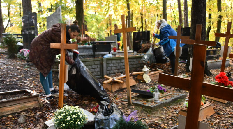 dwie osoby sprzątają na cmentarzu