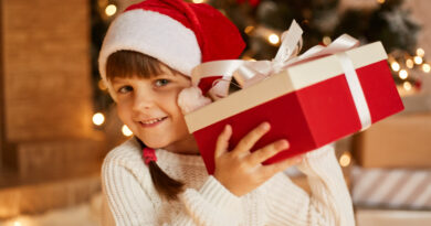 dziewczynka w czapce mikołaja trzyma prezent