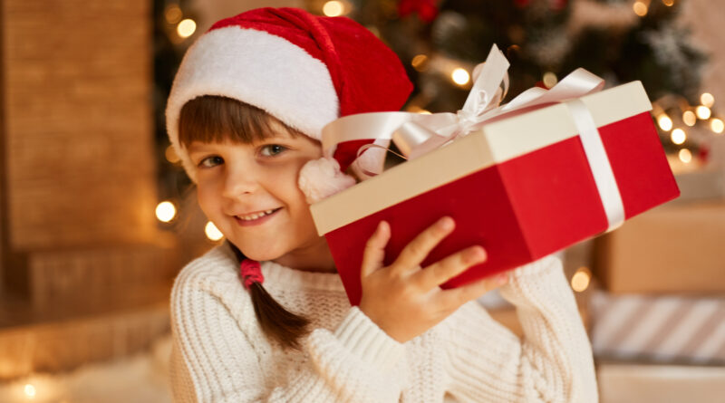 dziewczynka w czapce mikołaja trzyma prezent