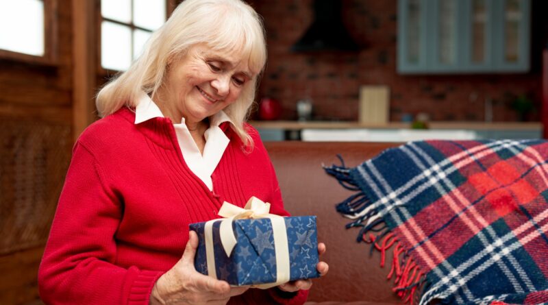 Starsza Pani trzyma w rękach zapakowany prezent