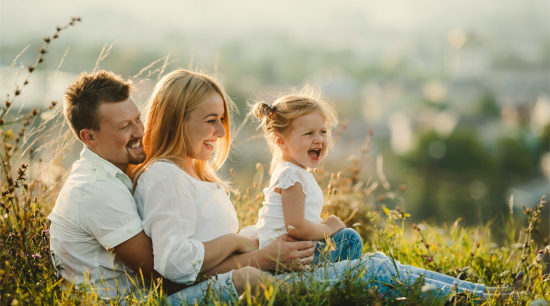 rodzice z małą dziewczynką siedzą na łące
